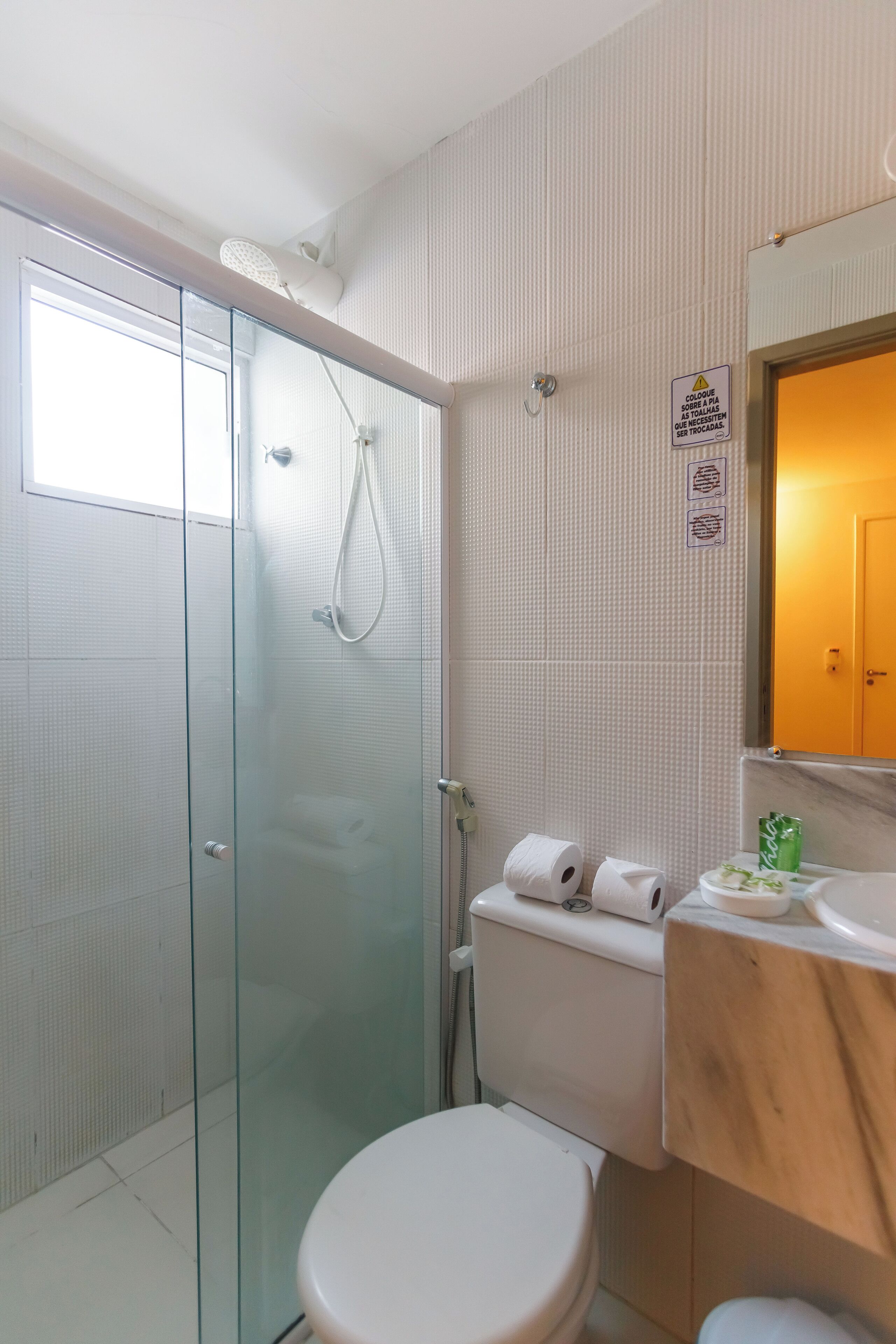 A bathroom with a glass shower enclosure, a toilet, and a sink with a mirror above it.