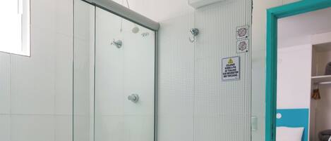 A modern bathroom with a glass shower enclosure, a white toilet, a marble sink, and a mirror with a blue frame.