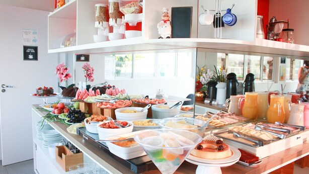 A buffet with various food items and a coffee station. - Zuza Slim Suítes (Maceió)