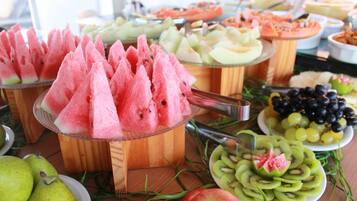 A buffet with various fruits and desserts, including watermelon, kiwi, grapes, and apple slices.