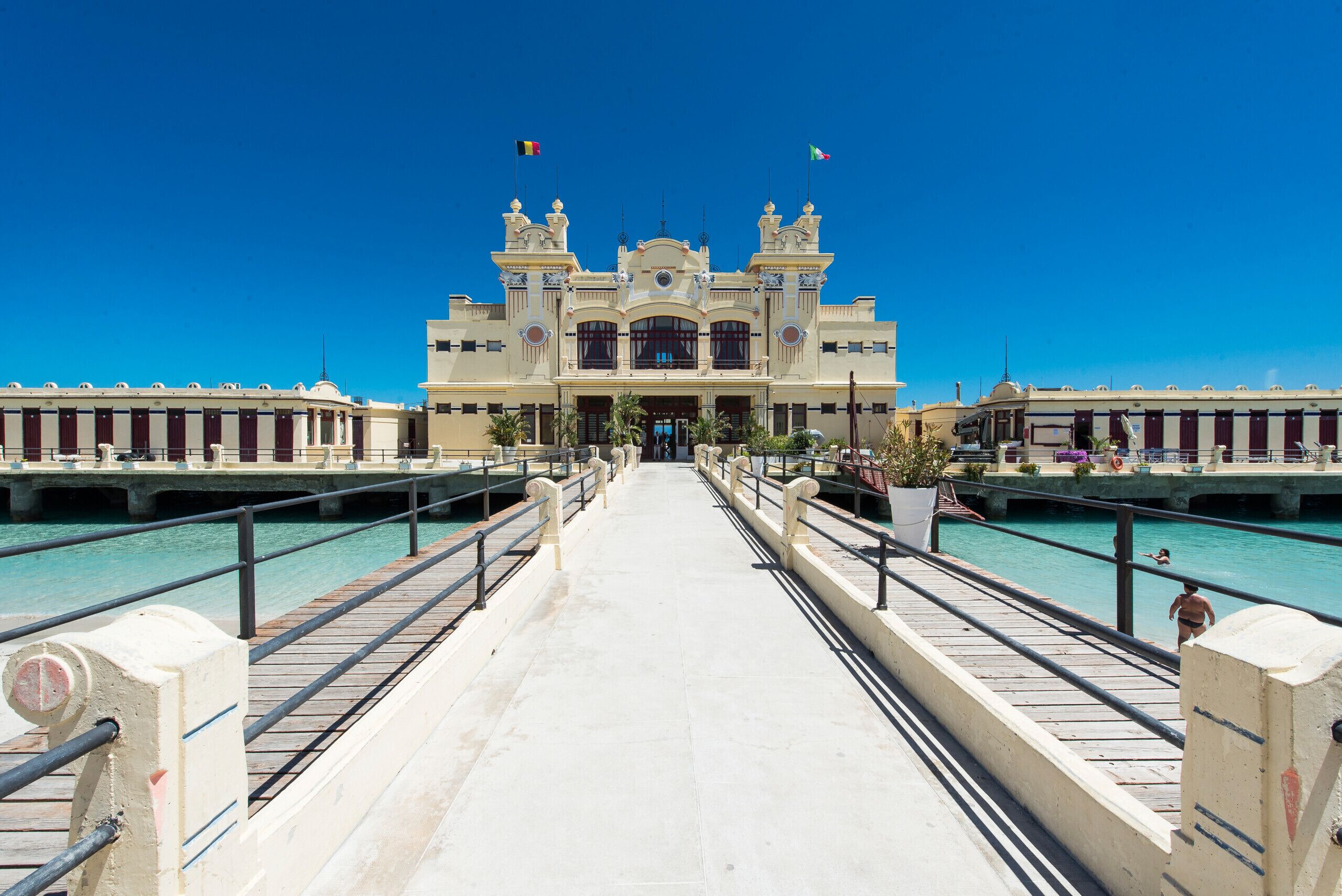 A grand building with a central entrance, flanked by two symmetrical wings, and a clear blue sky above.