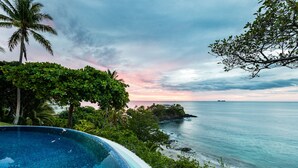 Piscina com vista para o oceano e um pôr do sol.