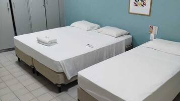Ein Hotelzimmer mit zwei Einzelbetten, einem Schrank, einem Tisch und einem gerahmten Bild an der Wand.