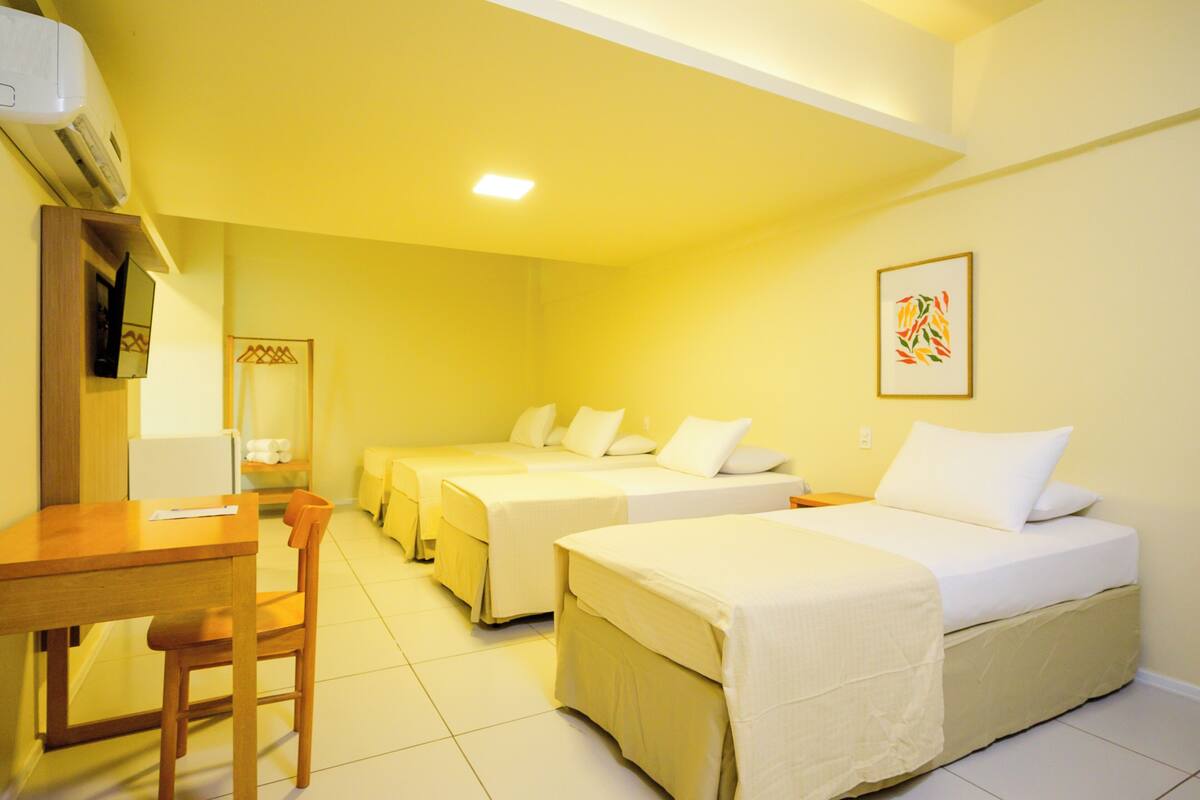 A hotel room with two single beds, a wooden desk, a chair, and a small table.