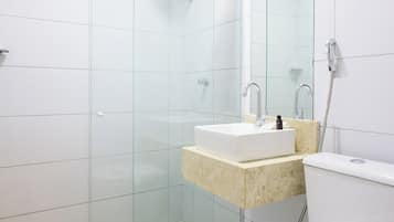 A modern bathroom with a glass-enclosed shower, a white sink, and a toilet.