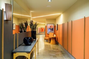 A modern hallway with a reception desk, seating area, and framed artwork on the walls. - Nordeste Palace Hotel - Fortaleza (Fortaleza)