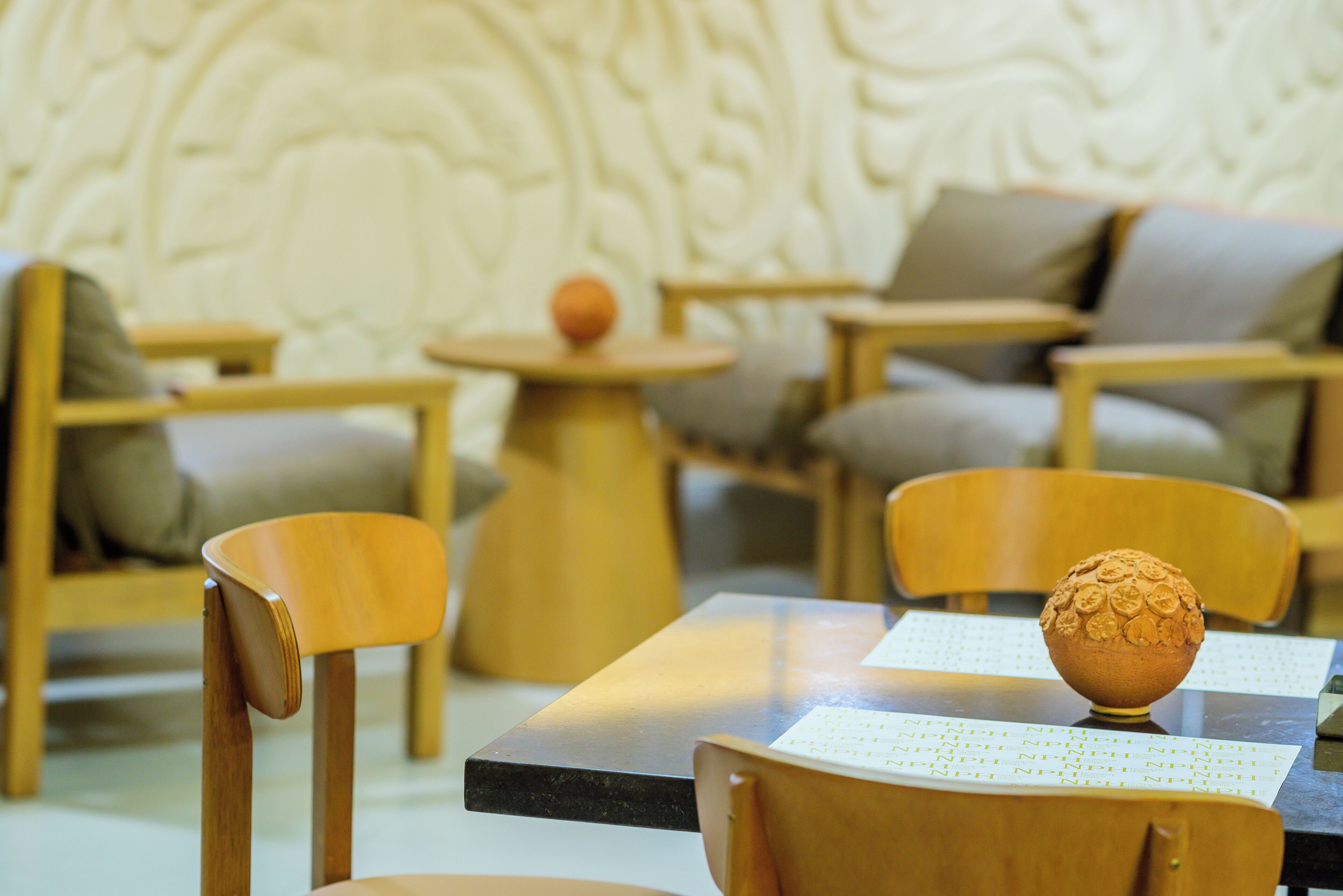 Una habitación moderna y bien iluminada con muebles de madera, incluyendo sillas y una mesa, y un cuenco decorativo sobre la mesa.