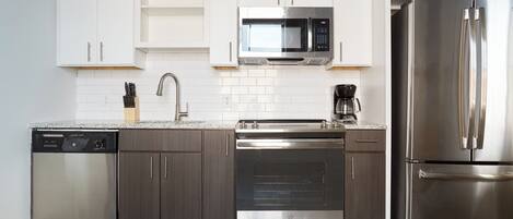 Una cocina moderna con electrodomésticos de acero inoxidable, armarios blancos y horno empotrado.