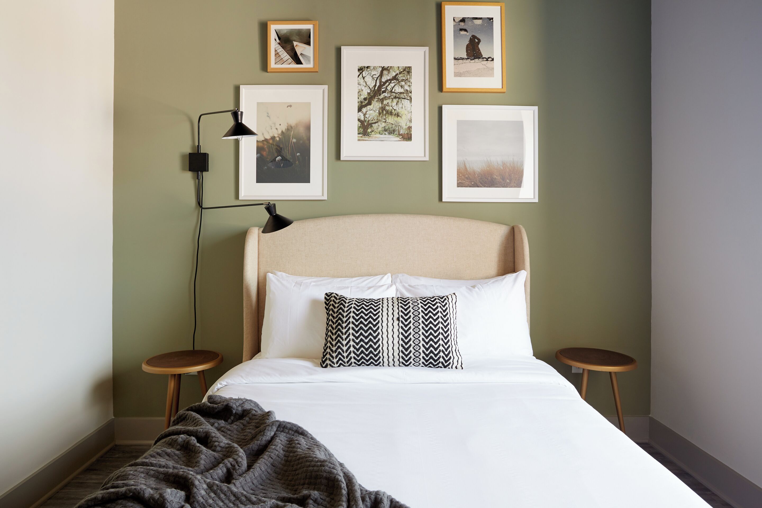 A neatly made bed with a patterned pillow, two bedside tables, and framed pictures on the wall.