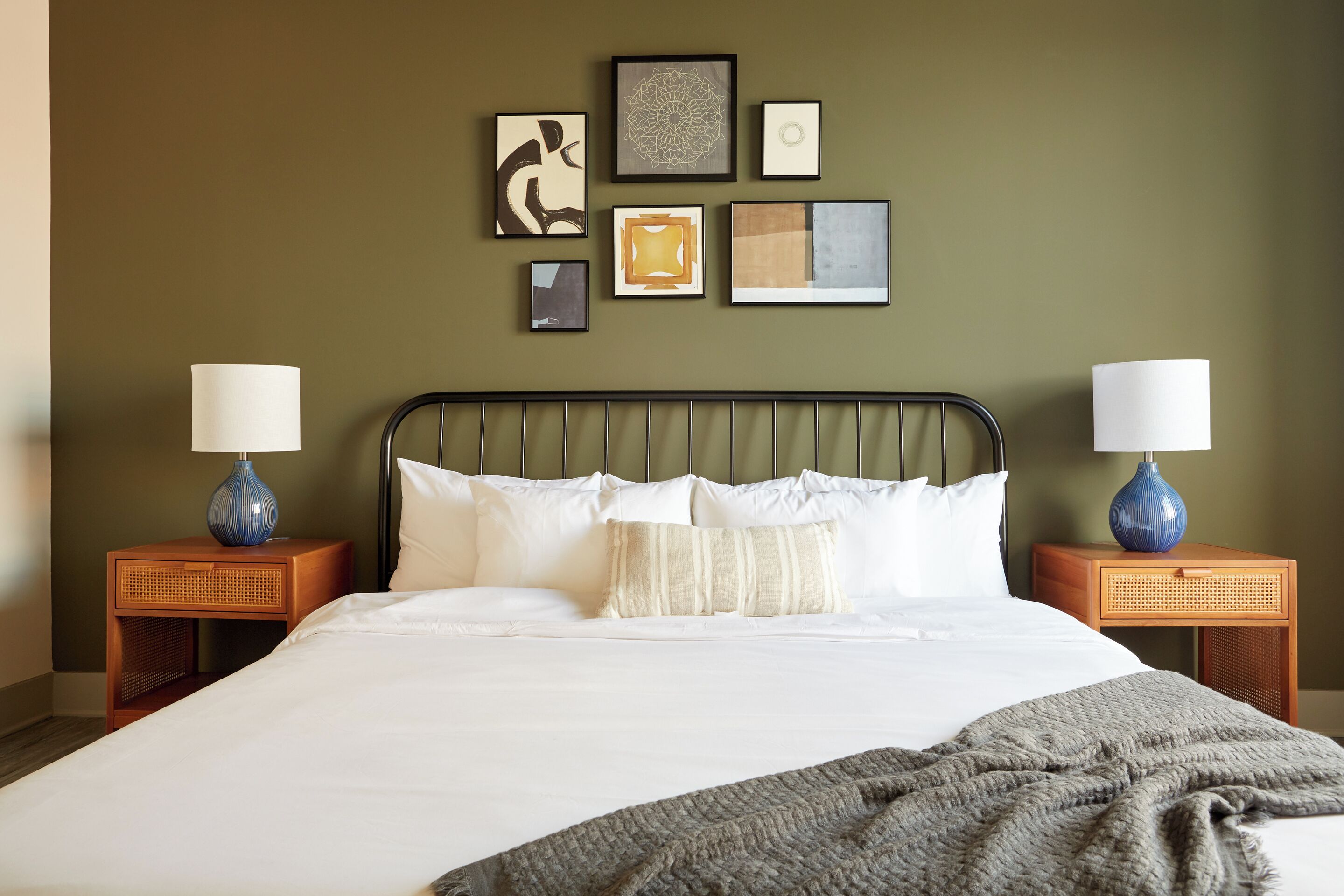 A neatly made bed with white linens, two bedside tables with lamps, and a wall adorned with framed artwork.