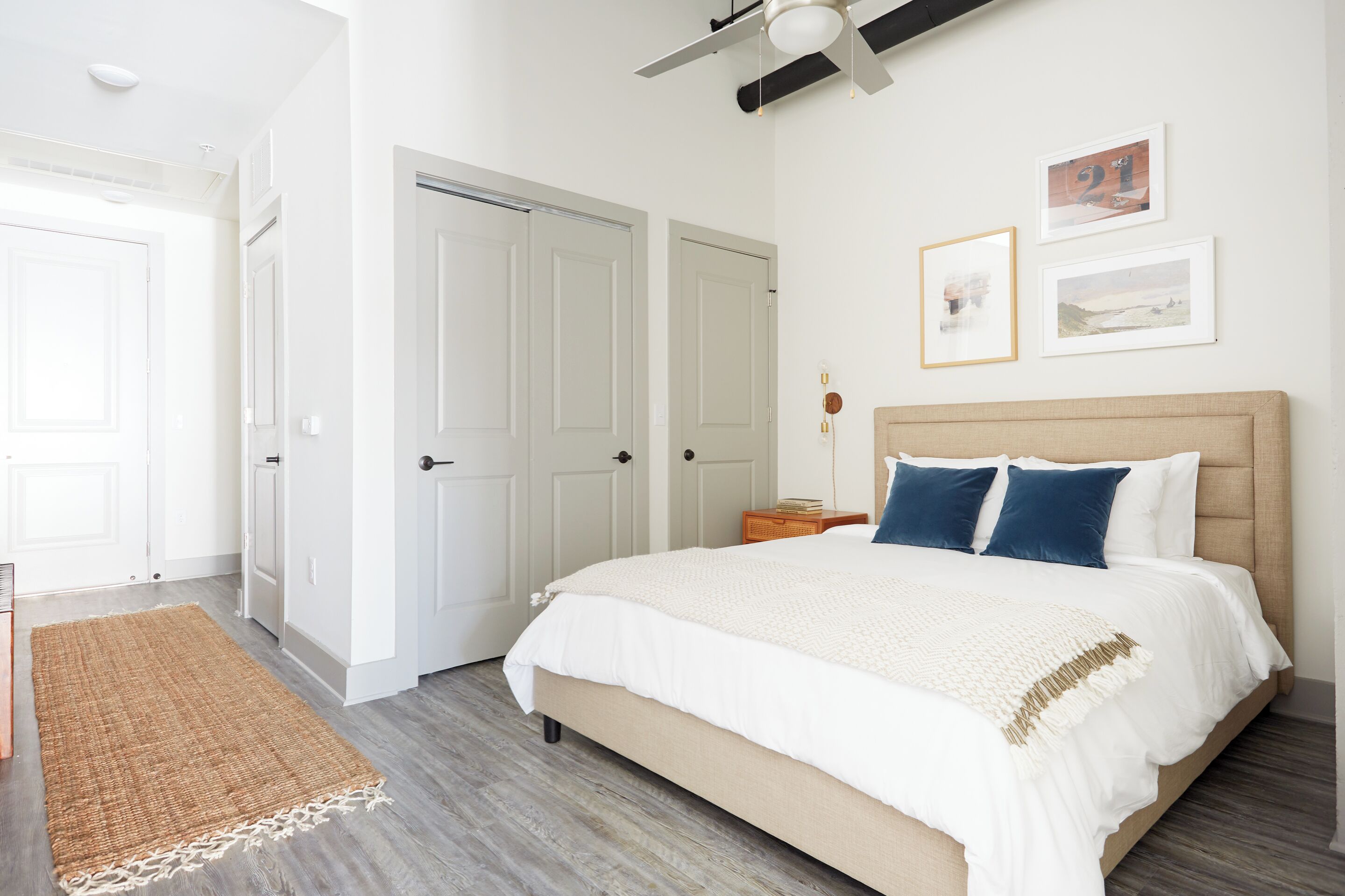 Une chambre à coucher avec un grand lit, des murs blancs et un ventilateur de plafond.