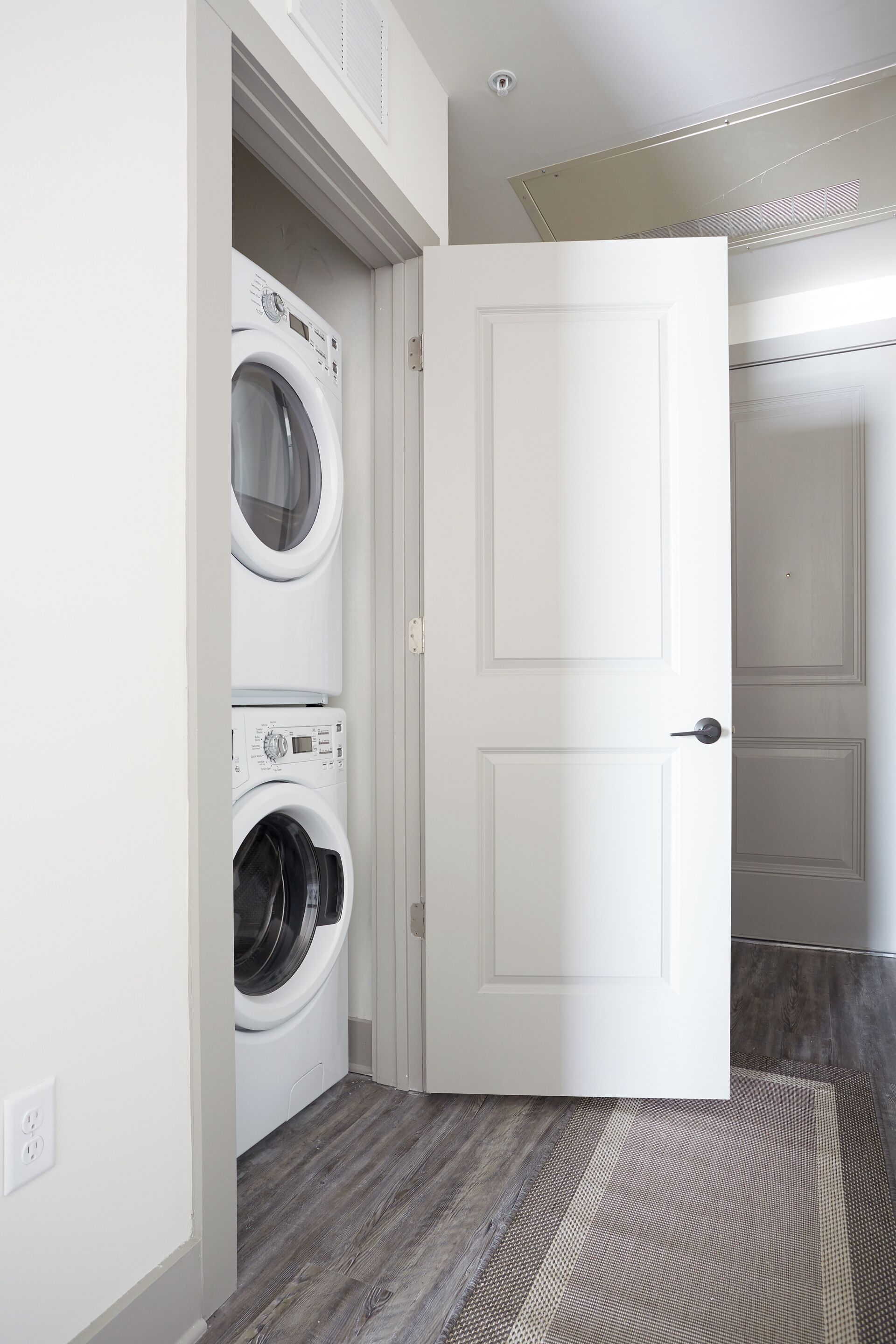 A laundry room with two stacked washing machines and a closed door.