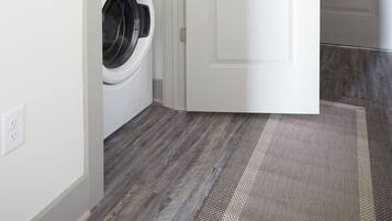 A laundry room with two stacked washing machines and a closed door.