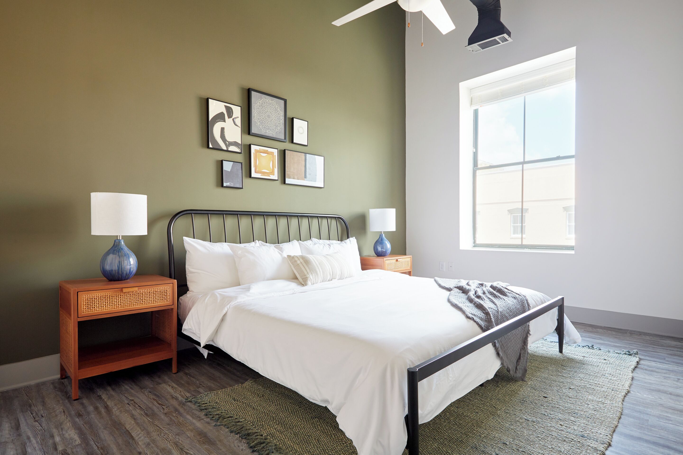 A bedroom with a bed, two nightstands, a window, and wall art.