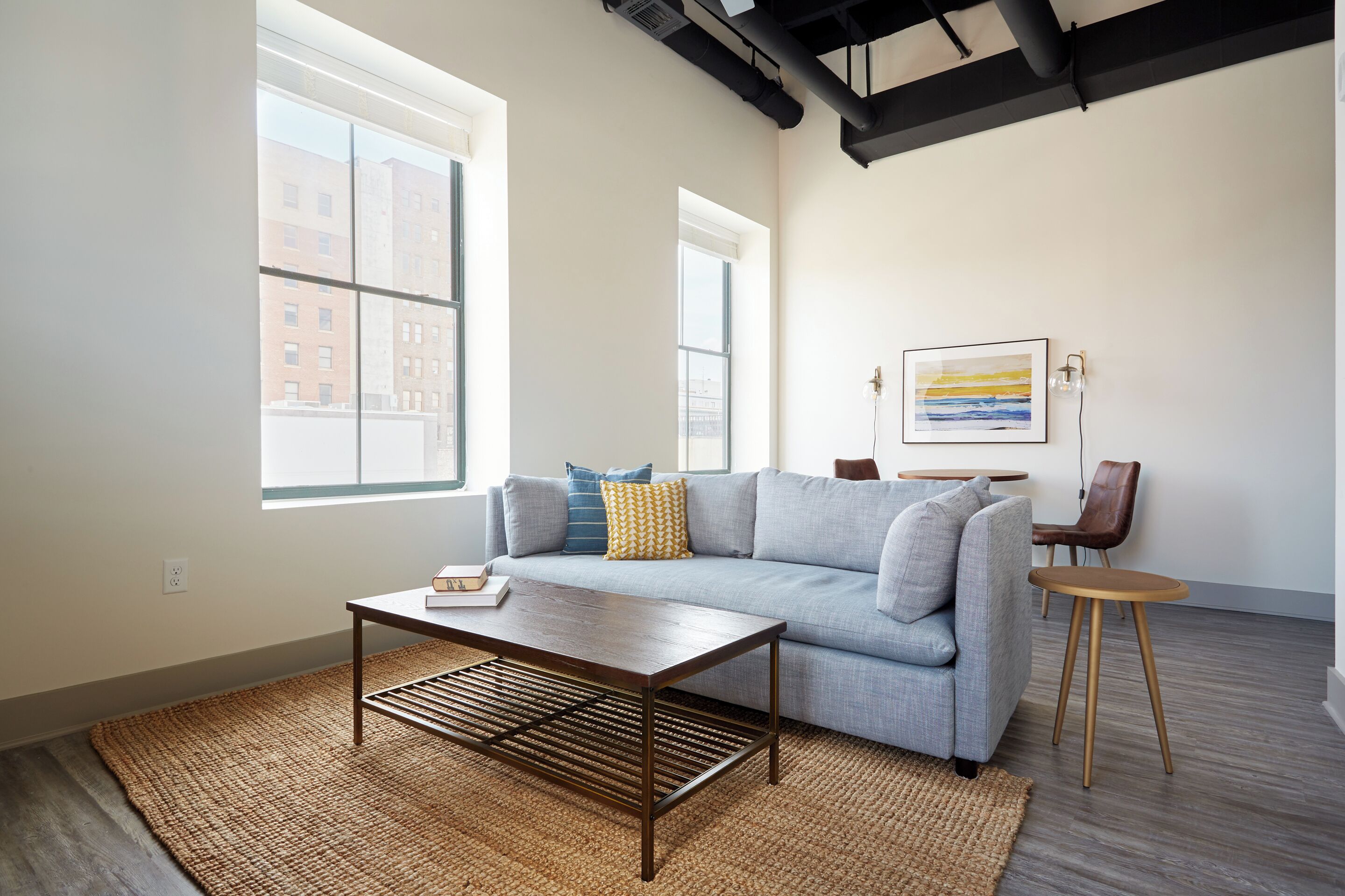 A modern living room with a sofa, coffee table, and a painting on the wall.