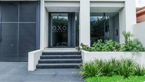 A modern building entrance with a glass door displaying the name "OXO BERTOIN". - OXO Bertoni Luxury in Villamorra (Asunción)