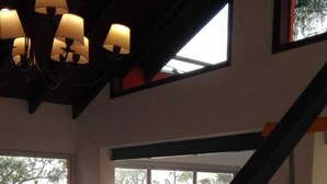A room with a staircase, a chandelier, and large windows overlooking a parking area. - Alojamiento La Roja (Chascomus)