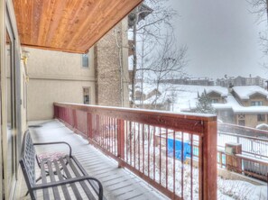 A wooden balcony with a bench, overlooking a snowy residential area with houses and bare trees. - Lift Tickets Ski To Your Door, Wifi, Deck, Hot Tub (Steamboat Springs)
