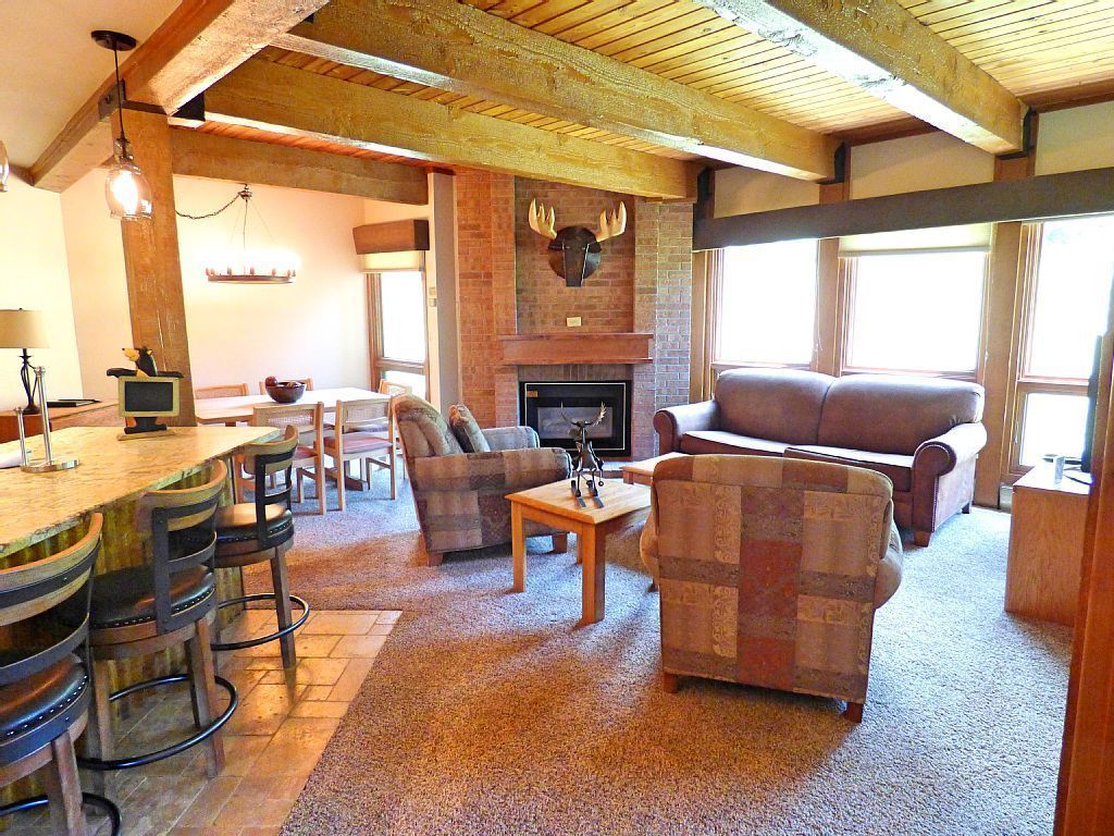 Una sala de estar acogedora con chimenea, vigas de madera y una ornamentación de piedra alrededor de la chimenea. Hay dos sofás y una mesa de centro.
