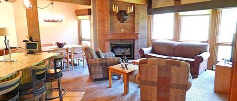 Una sala de estar acogedora con chimenea, vigas de madera y una ornamentación de piedra alrededor de la chimenea. Hay dos sofás y una mesa de centro.