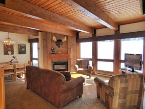 A cozy living room with a fireplace, wooden beams, a television, and comfortable seating.