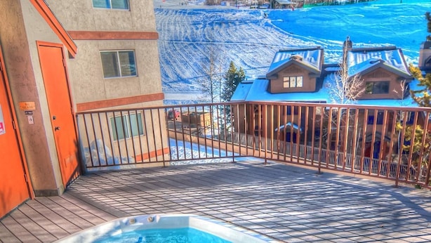 A hot tub on a wooden deck with a view of a snowy landscape and buildings in the background. - Lift Tickets Ski In Access & Hot Tub, Perfect For Couples (Steamboat Springs)