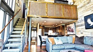 A loft-style living area with a high ceiling, a staircase, a sofa, and a dining area. - Lift Tickets Perfect Penthouse Rustic Finishes Fireplace (Steamboat Springs)
