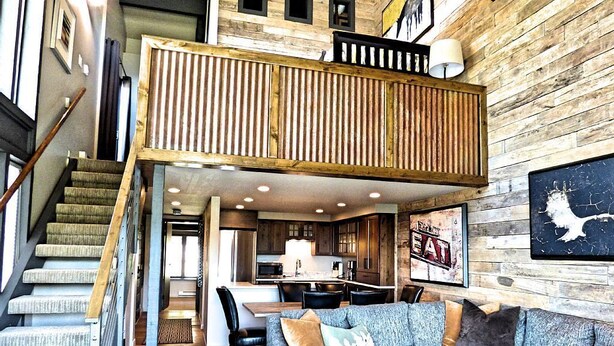 A loft-style living space with a staircase, a sofa, a dining area, and a kitchen. - Lift Tickets Perfect Penthouse Rustic Finishes Fireplace (Steamboat Springs)