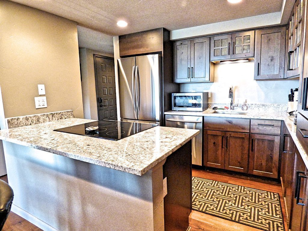 A kitchen with granite countertops, stainless steel appliances, and dark wooden cabinets.