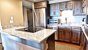 A kitchen with granite countertops, stainless steel appliances, and dark wooden cabinets. - Lift Tickets Perfect Penthouse Rustic Finishes Fireplace (Steamboat Springs)
