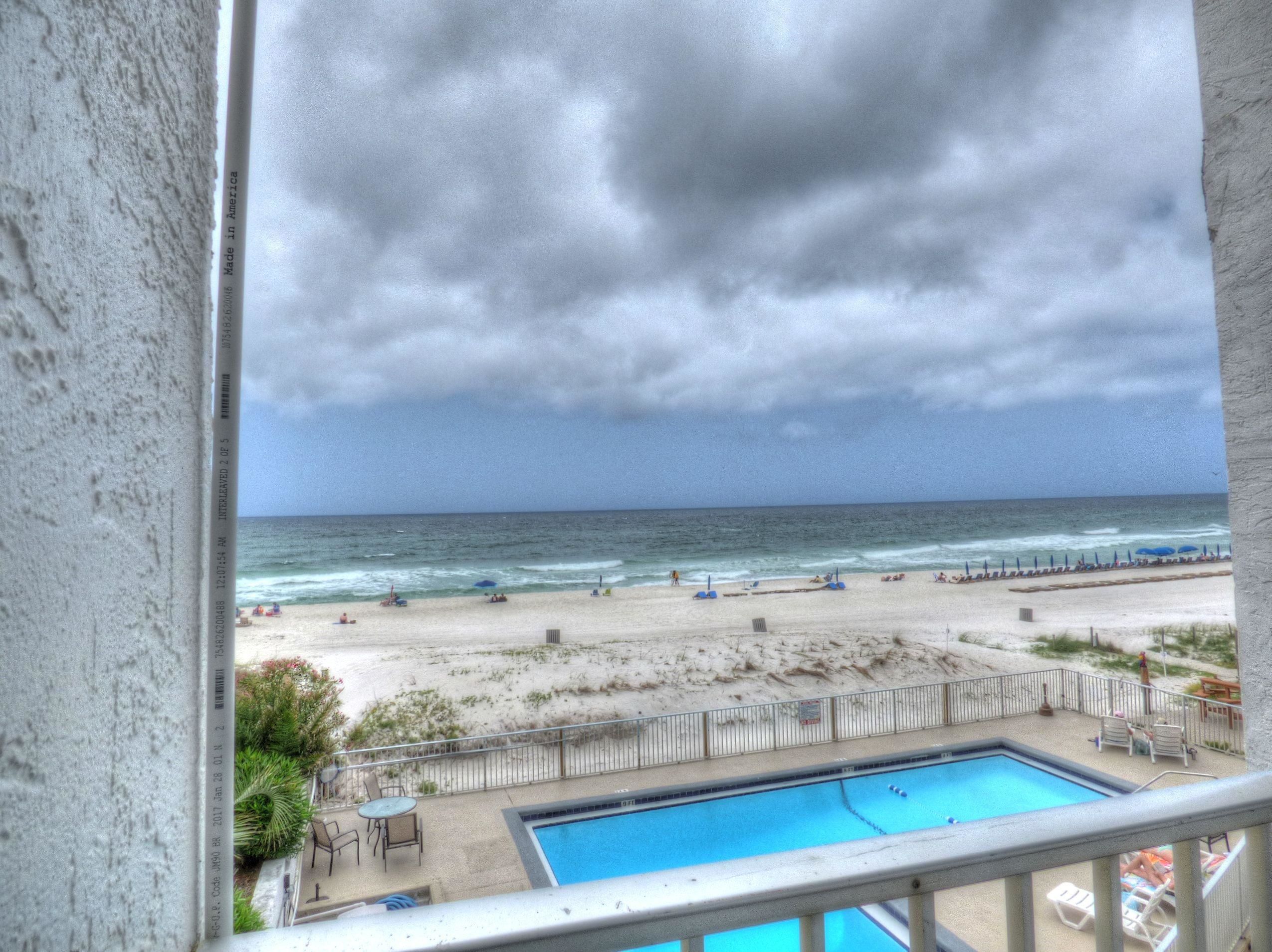 A view of a beach with a swimming pool and beach chairs.
