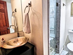 A bathroom with a wooden door, a sink with a soap dispenser, a towel ring, and a toilet. - Updated Mtn Front Garage Pkg Hottub Wifi Mtn Views Mtn Village Base (Steamboat Springs)