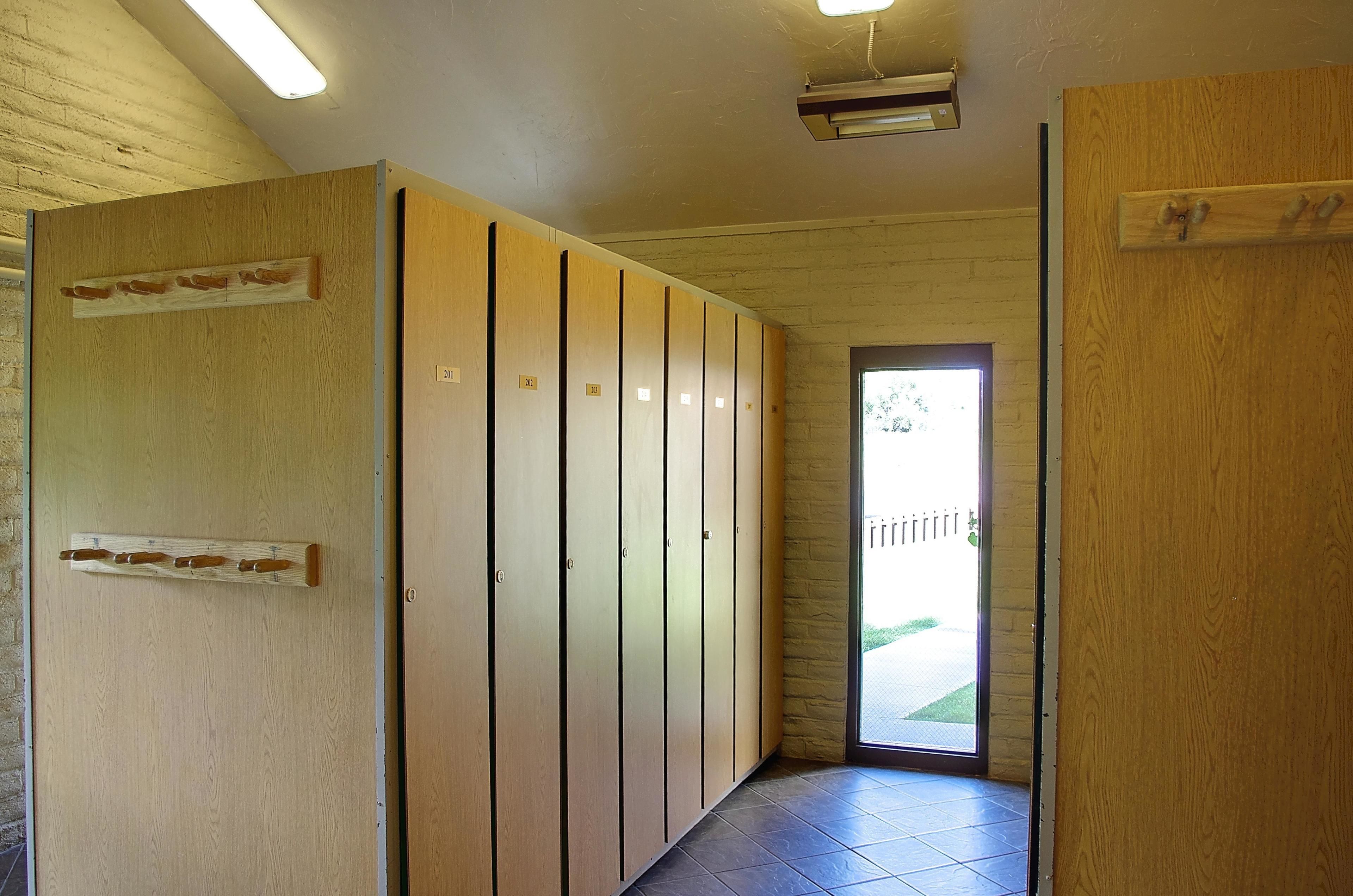 Un pasillo con taquillas de madera, una puerta que da al exterior y una lámpara en el techo.