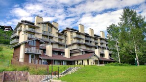 A multi-story hotel with balconies, a stone facade, and a grassy lawn. - Private Deck Mountain Views Babbling Creek Sleeps 4 (Steamboat Springs)
