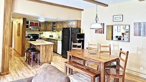 A kitchen with wooden beams, a dining table with chairs, a refrigerator, and a hanging light fixture. - Lift Tickets Ground Floor Pool, Hot Tubs, Near Mtn, Fireplace Shuttle (Steamboat Springs)