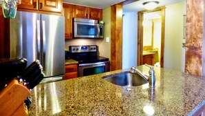 A kitchen with granite countertops, stainless steel appliances, wooden cabinets, and a built-in microwave. - Lift Tickets Shuttle & Hottub, Pool, Near Ski Mountain Area (Steamboat Springs)