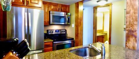 A kitchen with granite countertops, stainless steel appliances, wooden cabinets, and a built-in microwave.
