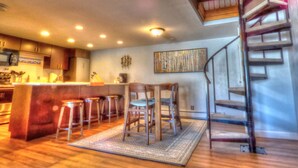 A modern kitchen with a central island, bar stools, and a spiral staircase. - Lift Tickets Pool, Hot Tubs, Shuttle & Private Deck Mountain Village (Steamboat Springs)