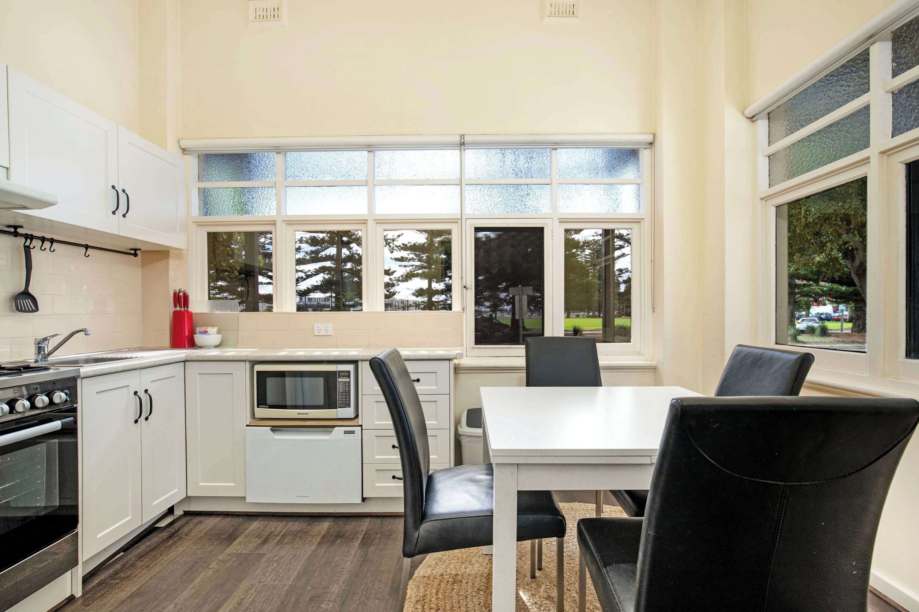 A kitchen with white cabinets, a microwave, a stove, and a dining area with a table and chairs.