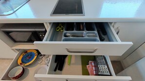 Un cajón de cocina con utensilios, un microondas y un plato colorido.