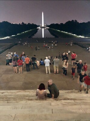 Stroll through the serene, open plaza surrounded by a low wall, featuring a striking monument at its center.