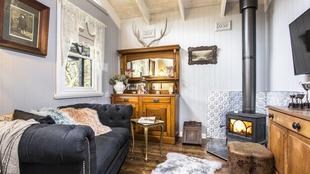 Ein gemütliches Wohnzimmer mit Kamin, einer Couch, einem Holzschrank und einem dekorativen Spiegel.