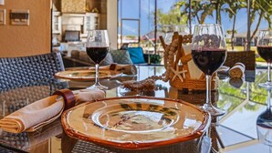 A dining table set with plates, glasses, and napkins, with a view of palm trees and a building in the background. - Backyard Oasis, Luxurious, Magnificent-Villa Triton's Tide- Cape Coral- Roelens Vacations (Cape Coral)
