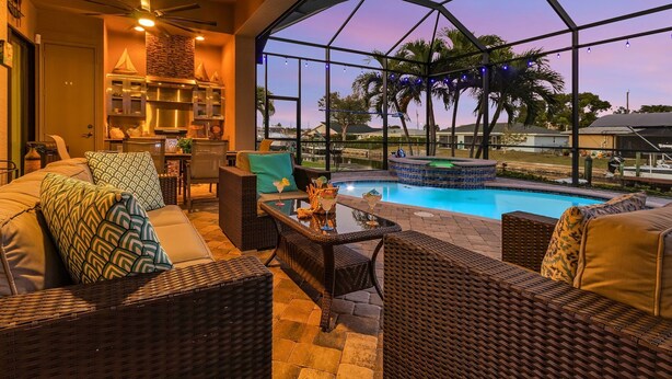 A spacious indoor area with a pool, wicker furniture, and a ceiling fan. - Backyard Oasis, Luxurious, Magnificent-Villa Triton's Tide- Cape Coral- Roelens Vacations (Cape Coral)