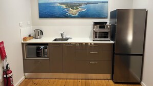 A modern kitchen with a stainless steel refrigerator, a microwave, and a toaster oven on the countertop.