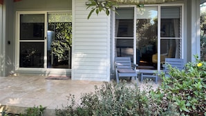 A house with a covered porch, sliding glass doors, and outdoor seating.