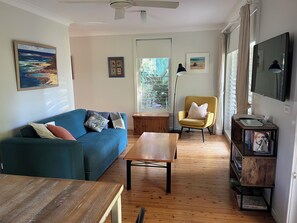 A living room with a blue sofa, a wooden coffee table, a yellow armchair, and a bookshelf.