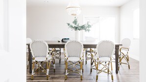 A dining area with a wooden table and six wicker chairs. - Charming Home  - Sleeps 14 + Heated Pool + BBQ + 5-7 minutes to Old Town (Scottsdale)