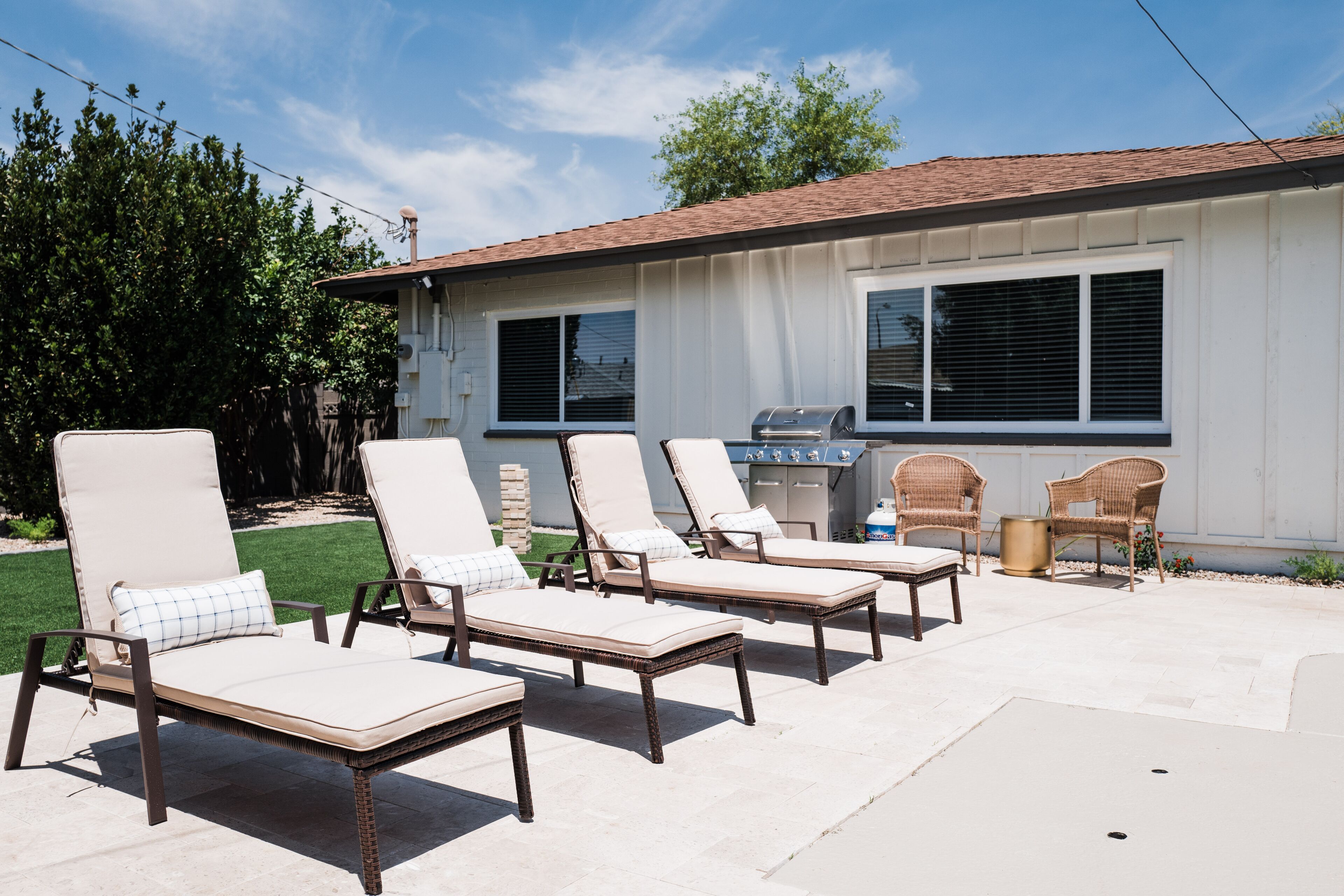 A patio with four lounge chairs and a grill area.
