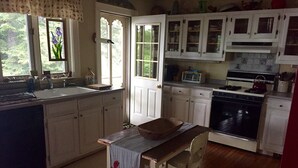 Une cuisine avec des meubles blancs, une cuisinière, un four à micro-ondes et un évier.